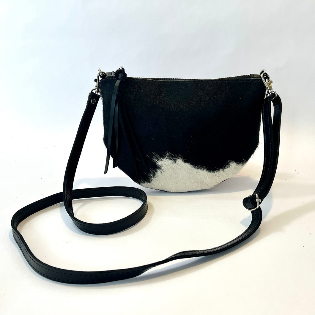 Handcrafted leather cowhide crossbody bag with zippered closure in black and white spotted hair on hide